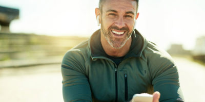 Man smiling while jogging and looking at phone.