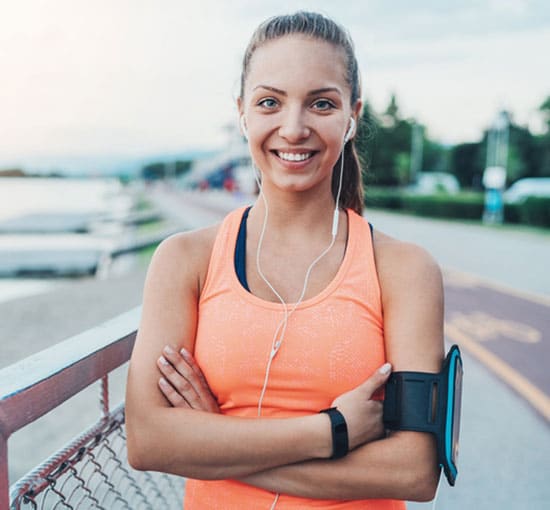 Woman standing with peach tank top during run.