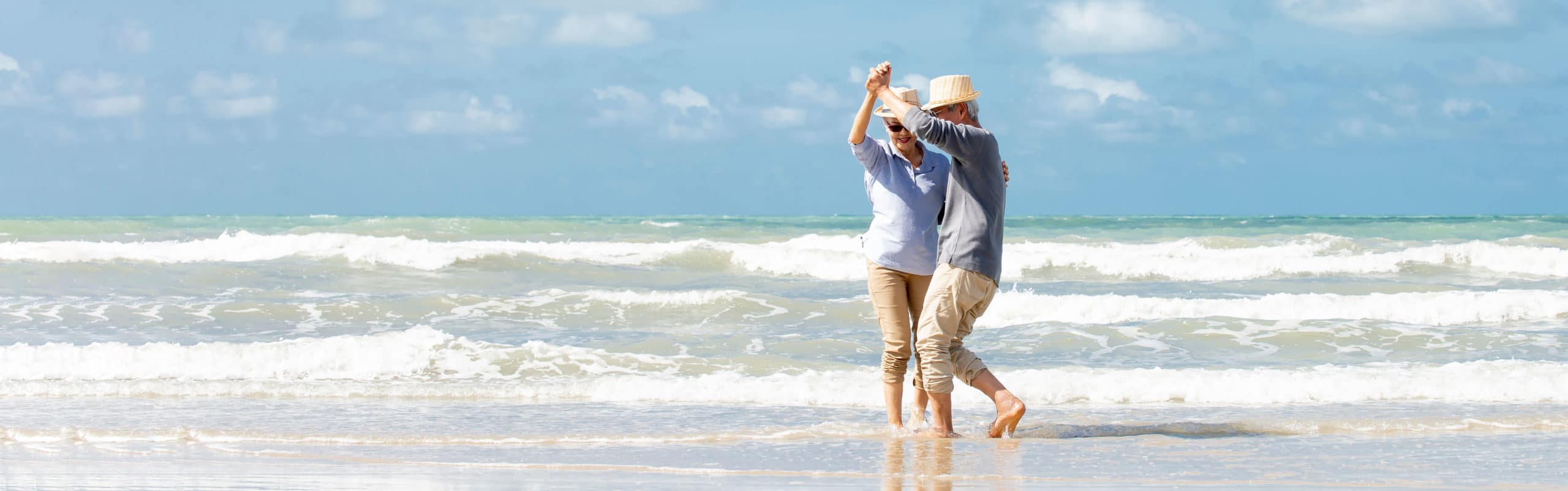 Happy asian senior couple  dancing  on the beach with blue sky background , Retirement travel  holiday healthy lifestyle Concept , Banner for text