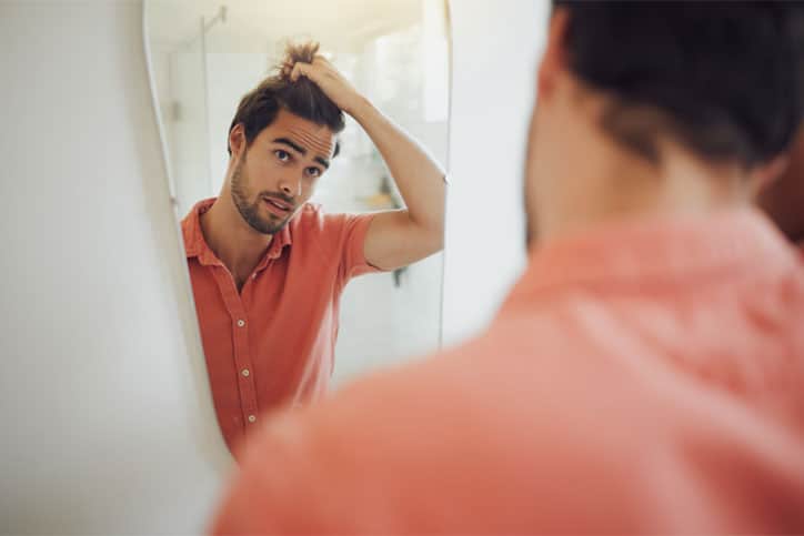 Man looking at Hair in Mirror