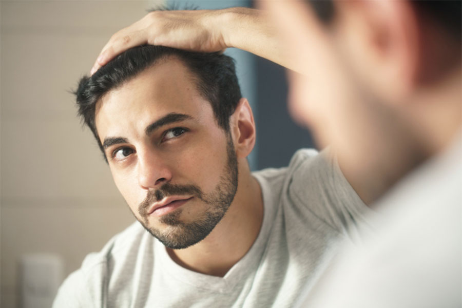 Man Looking At Hair in Mirror
