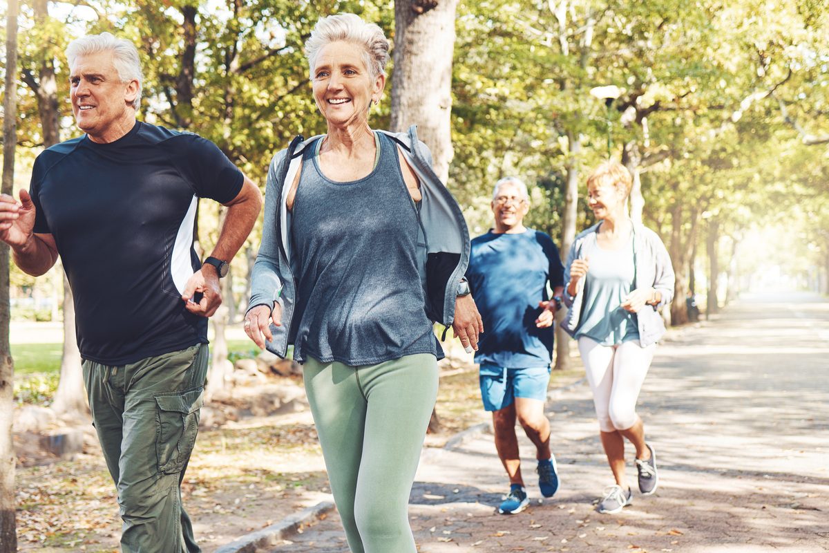 Active seniors jogging on a tree-lined path
