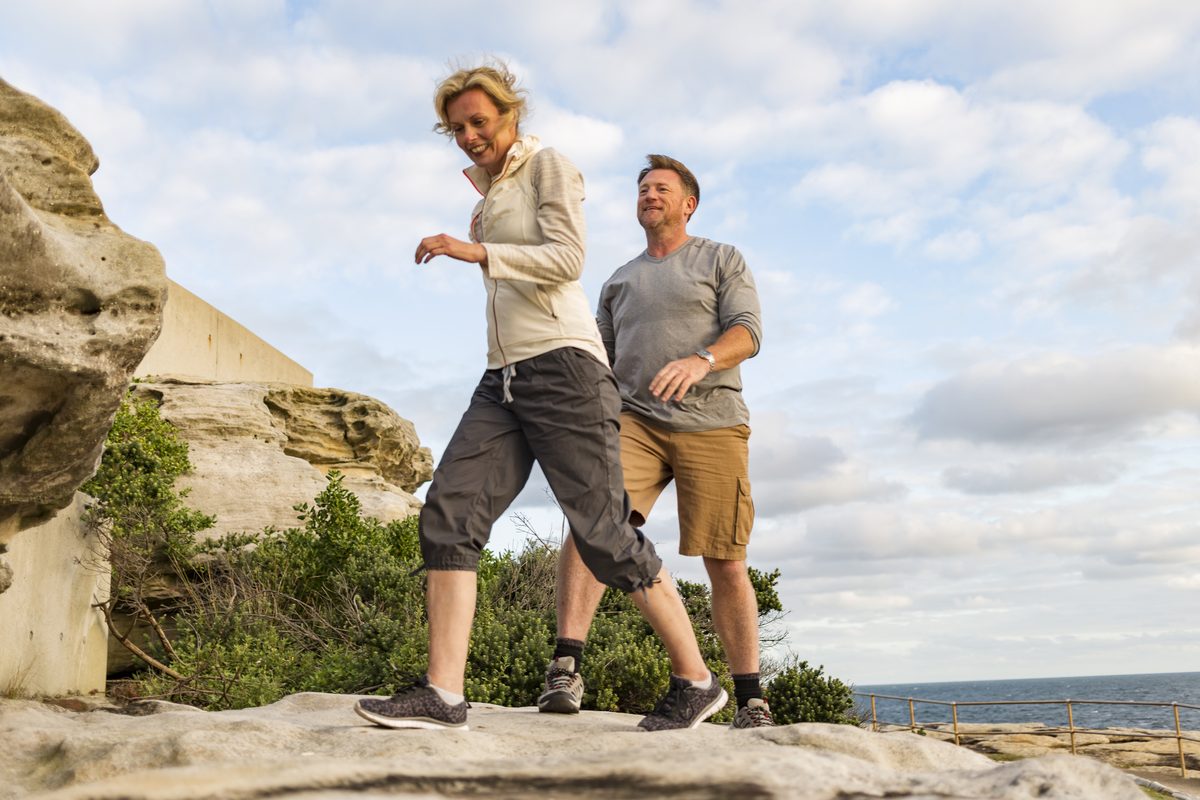 Older couple smiling while hiking along rocky Great Lakes shoreline