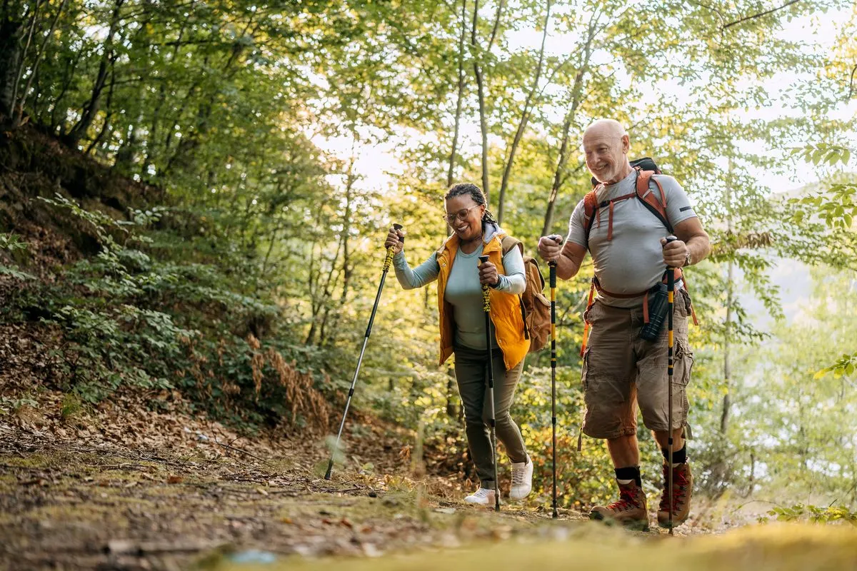 Couple hiking uphill together with trekking poles