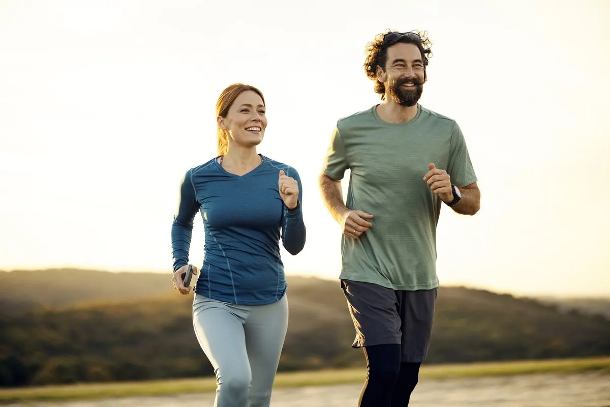 A man and a woman jogging outdoors at sunset.