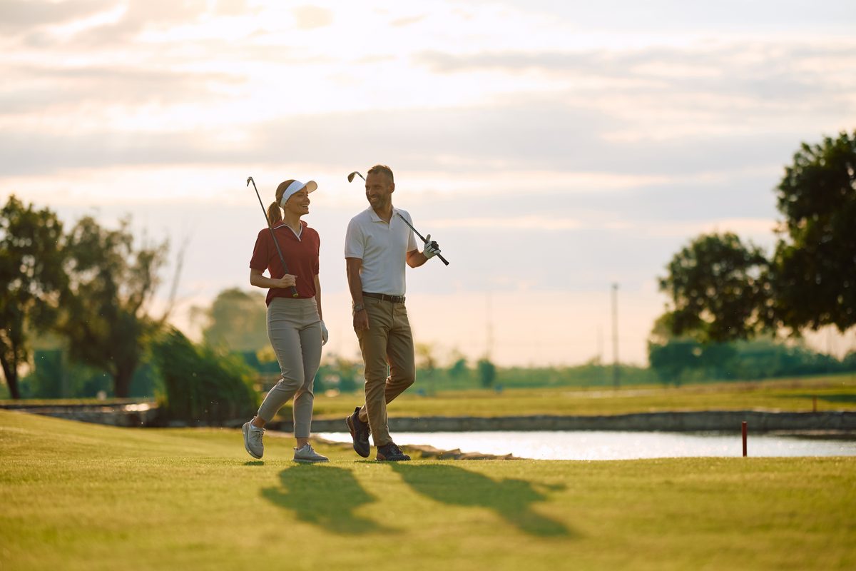 Couple walking across a golf course at sunset