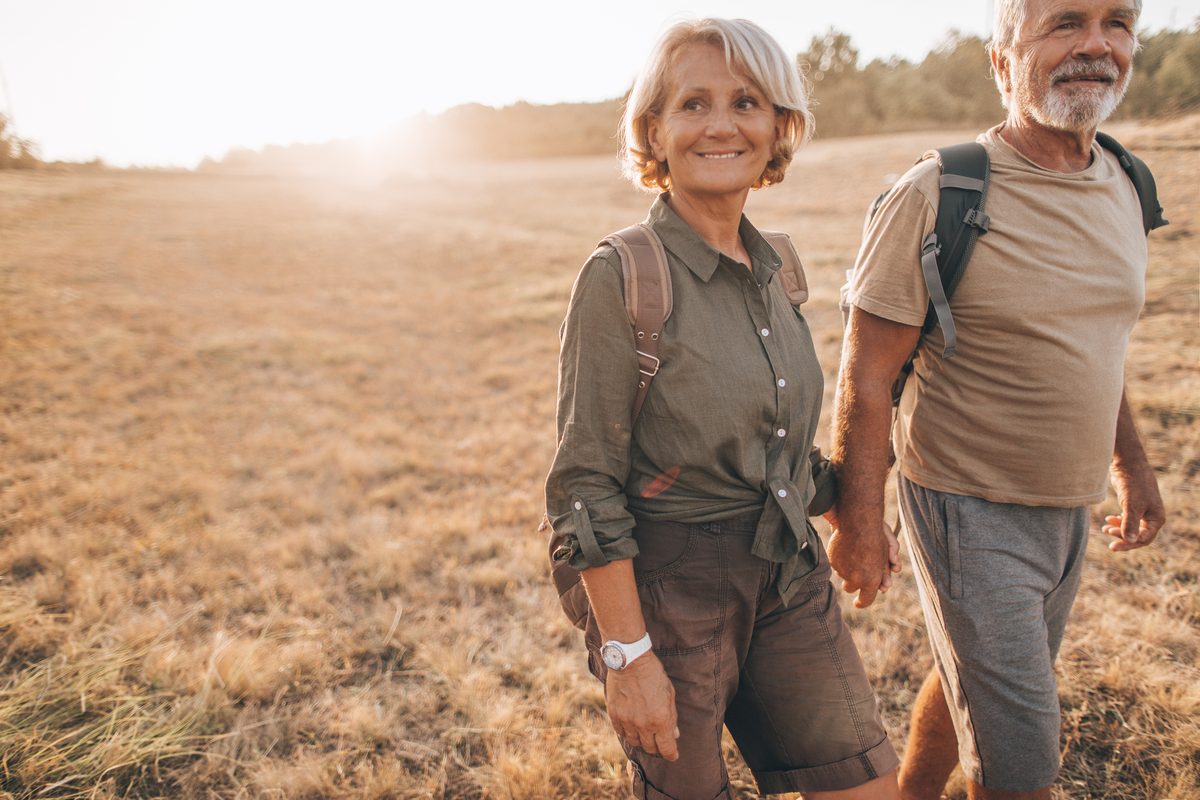 Couple walking hand in hand through a sunny field