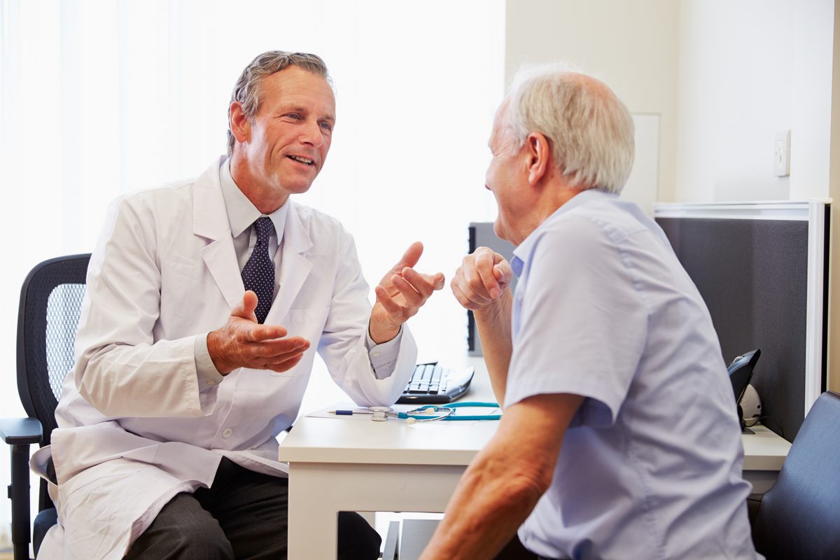 A doctor chats with an older man at a desk