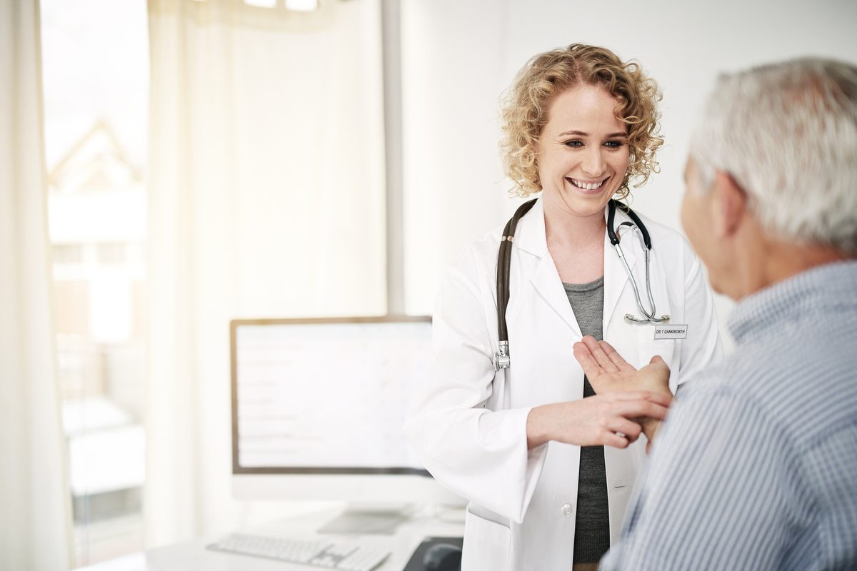 A doctor examines an older man’s wrist