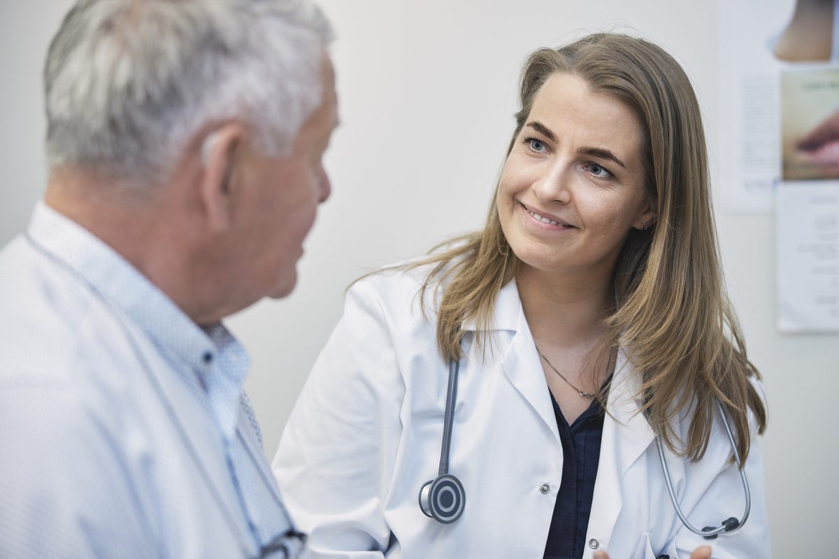 A physician listens closely to an older man during an exam room visit