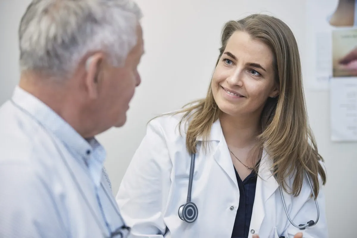 Smiling doctor talking with an older male patient in an exam room