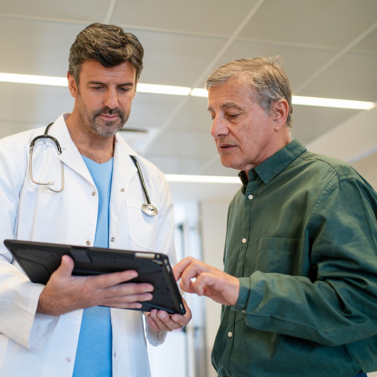 Doctor showing a tablet to an older male patient