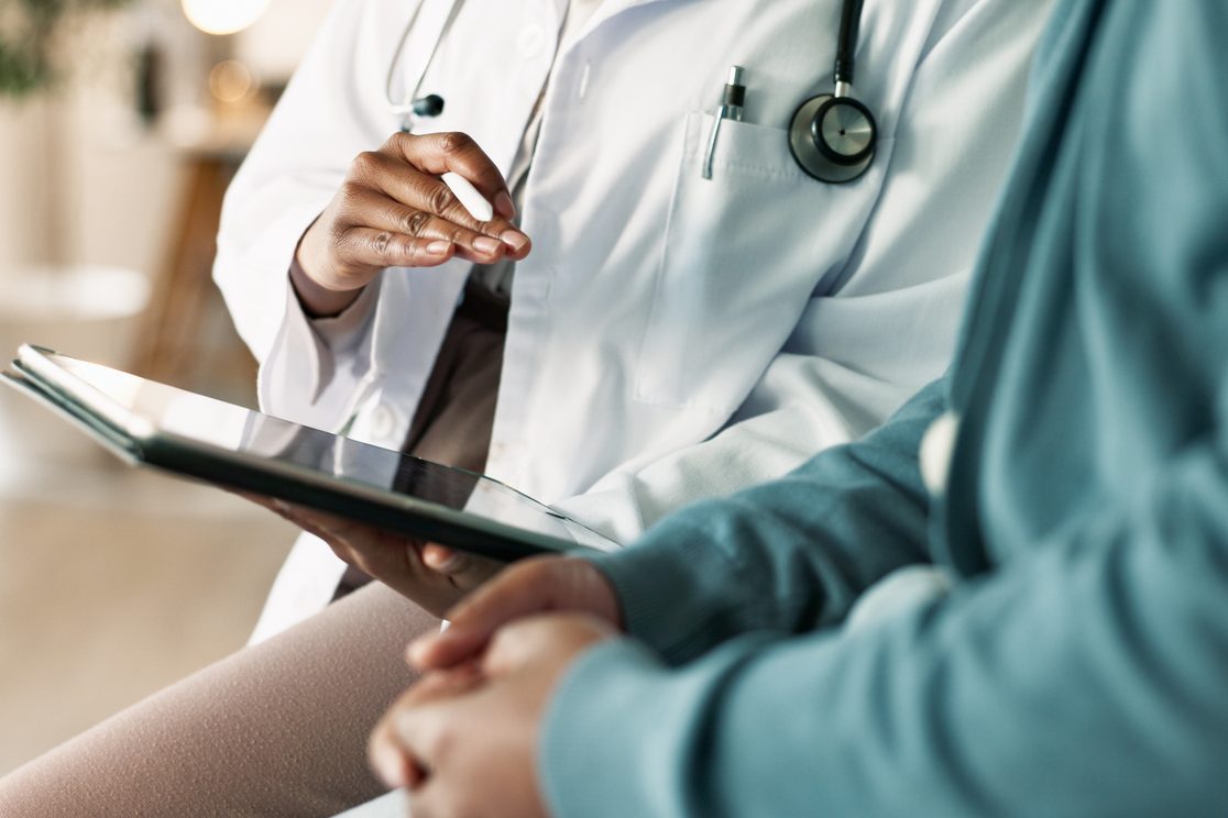 Close-up of a doctor showing a patient information on a tablet