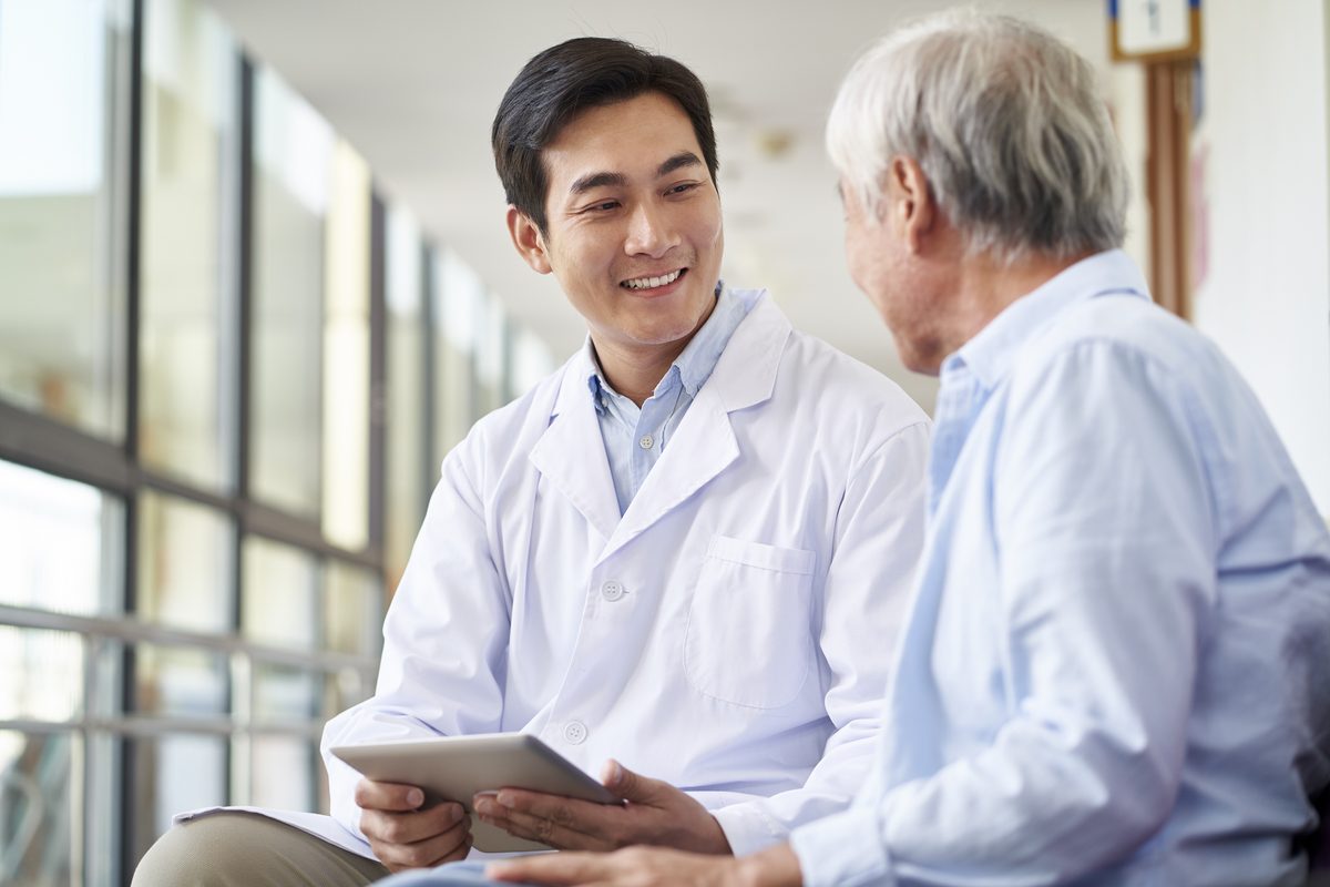 A doctor with a tablet talks to an older man