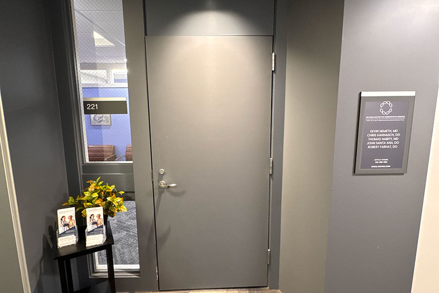 Entrance to the Michigan Center for Regenerative Medicine in Grand Rapids, featuring a sign listing the physicians and a side table with brochures.