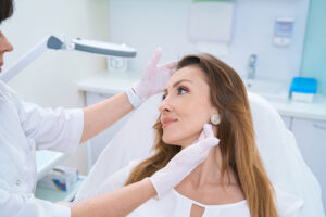 A practitioner wearing gloves examines a patient’s face at a regenerative medicine clinic.