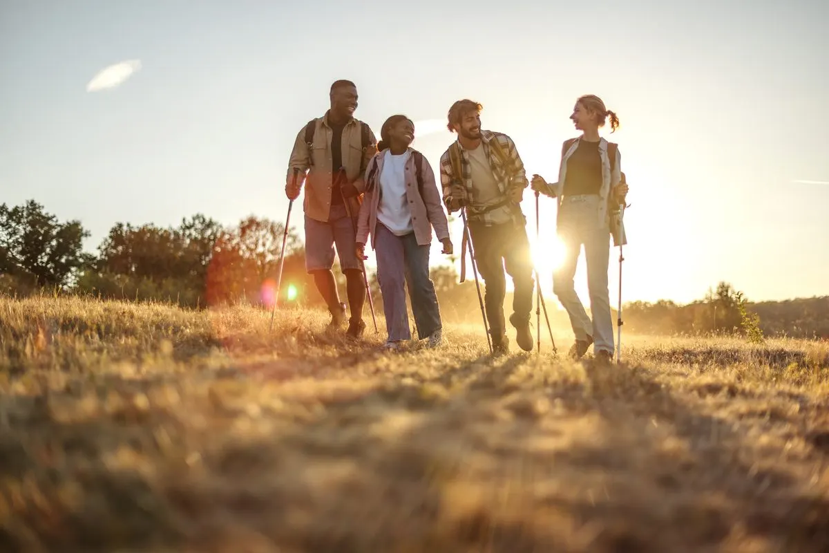 Friends hiking through a meadow at sunset