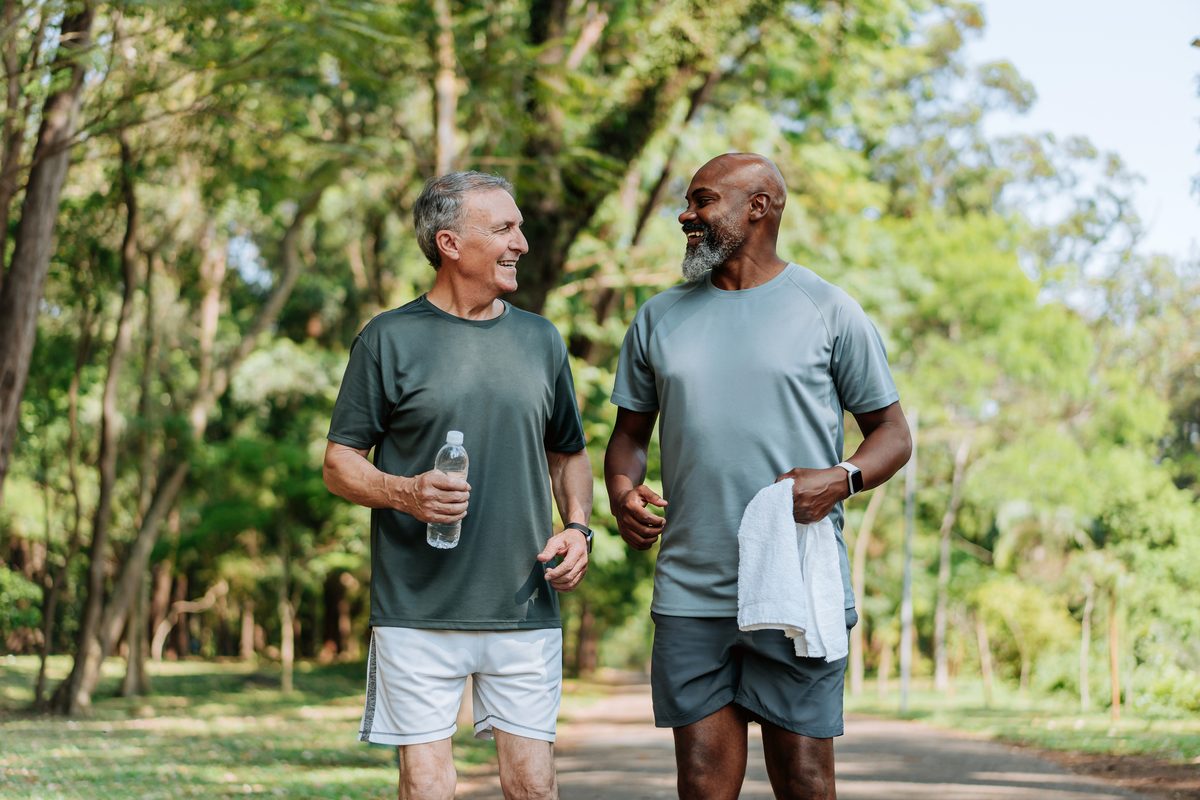 Two friends walk a park trail carrying water bottles