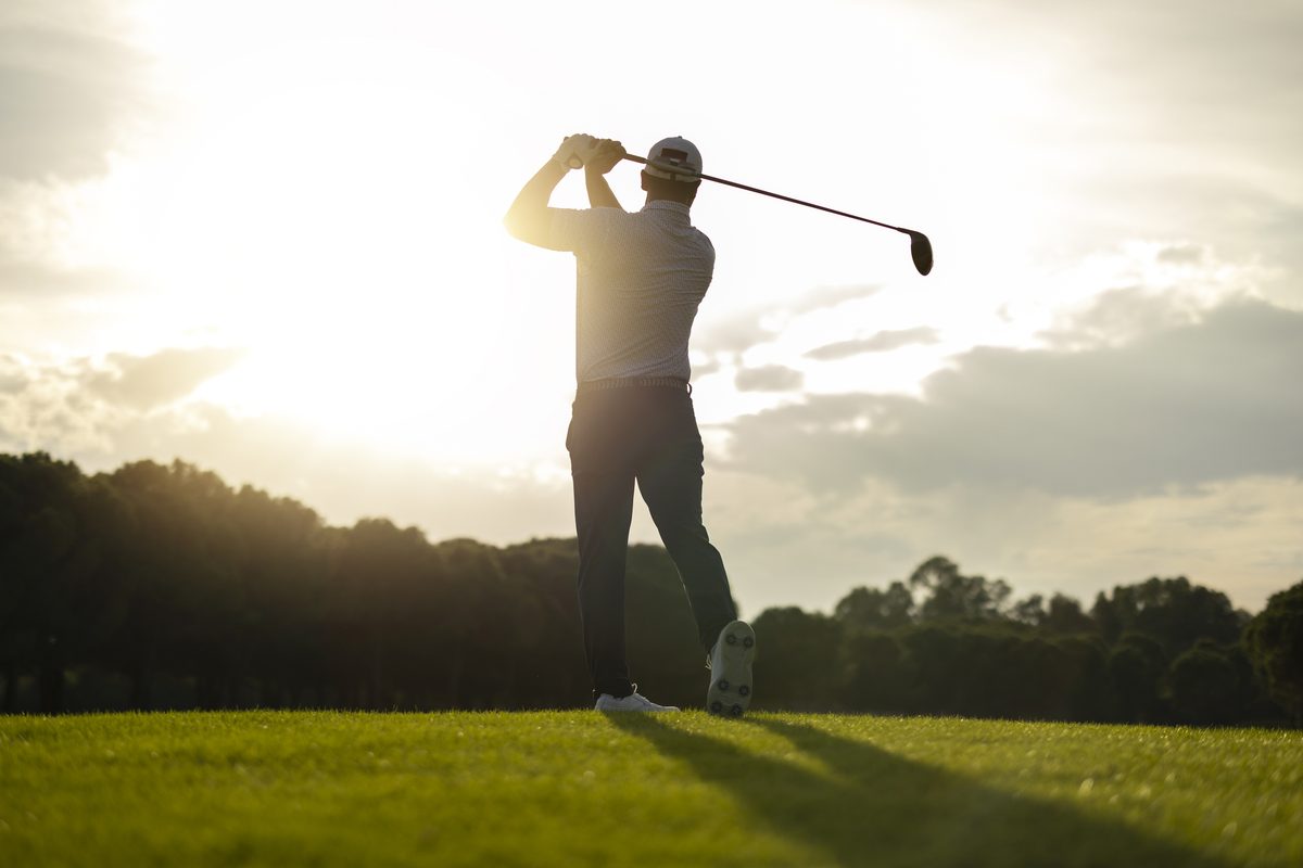 Golfer swinging at sunrise