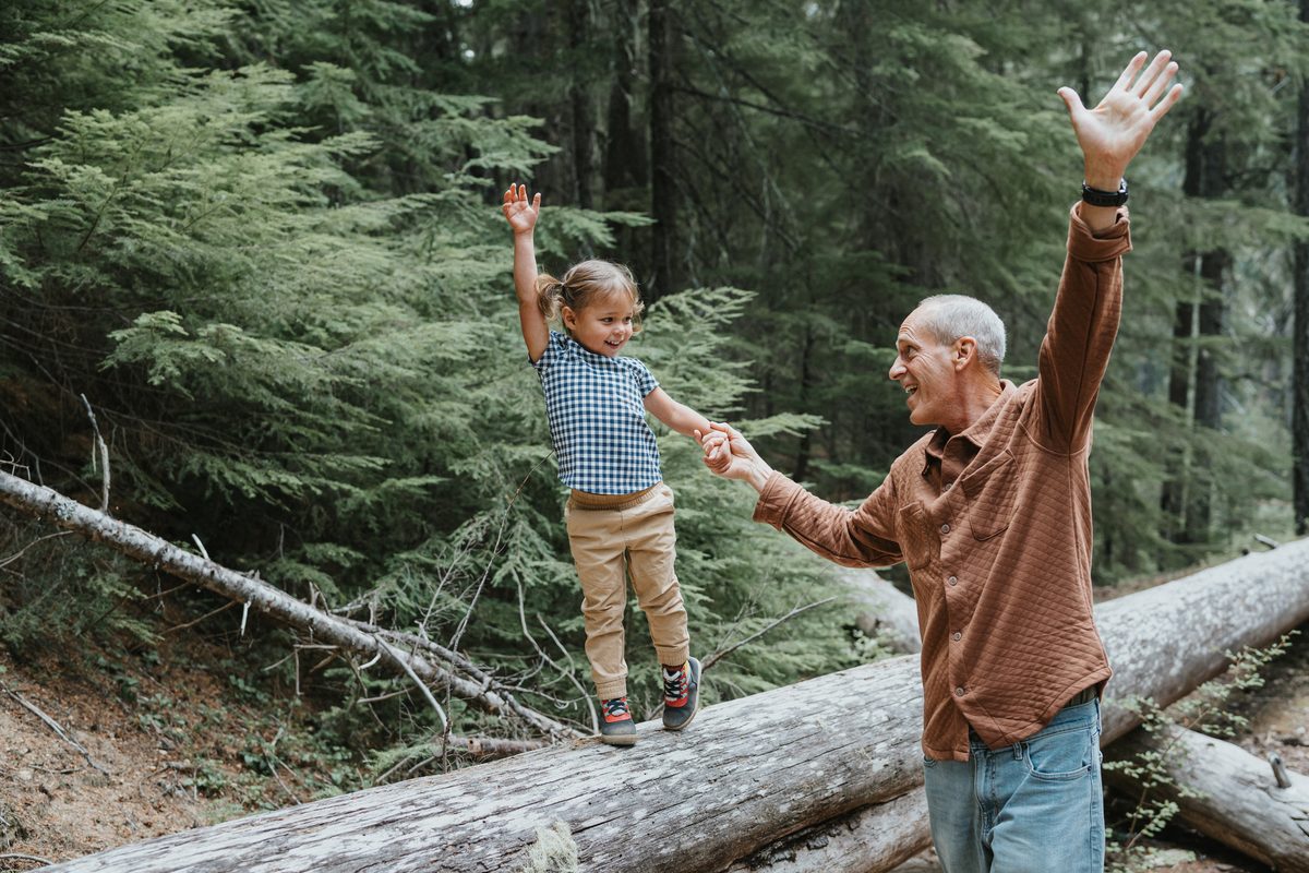 Grandfather and granddaughter smiling on a hike