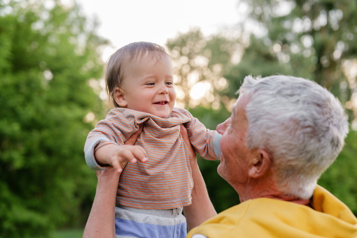 Grandfather lifting a baby outdoors