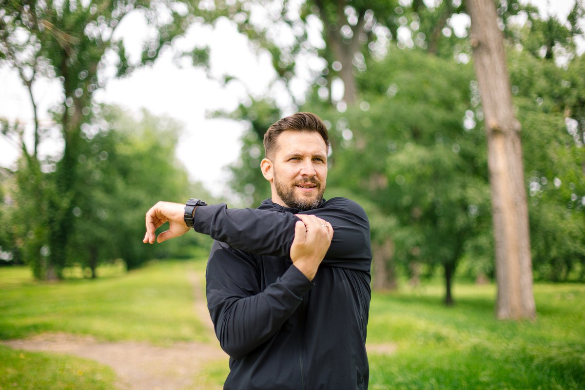 Man stretching his shoulder in a park