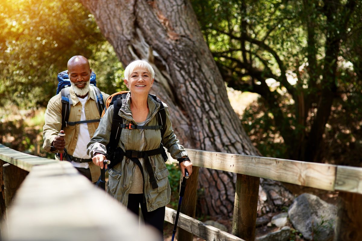 Older couple walking together on a wooden boardwalk through the forest