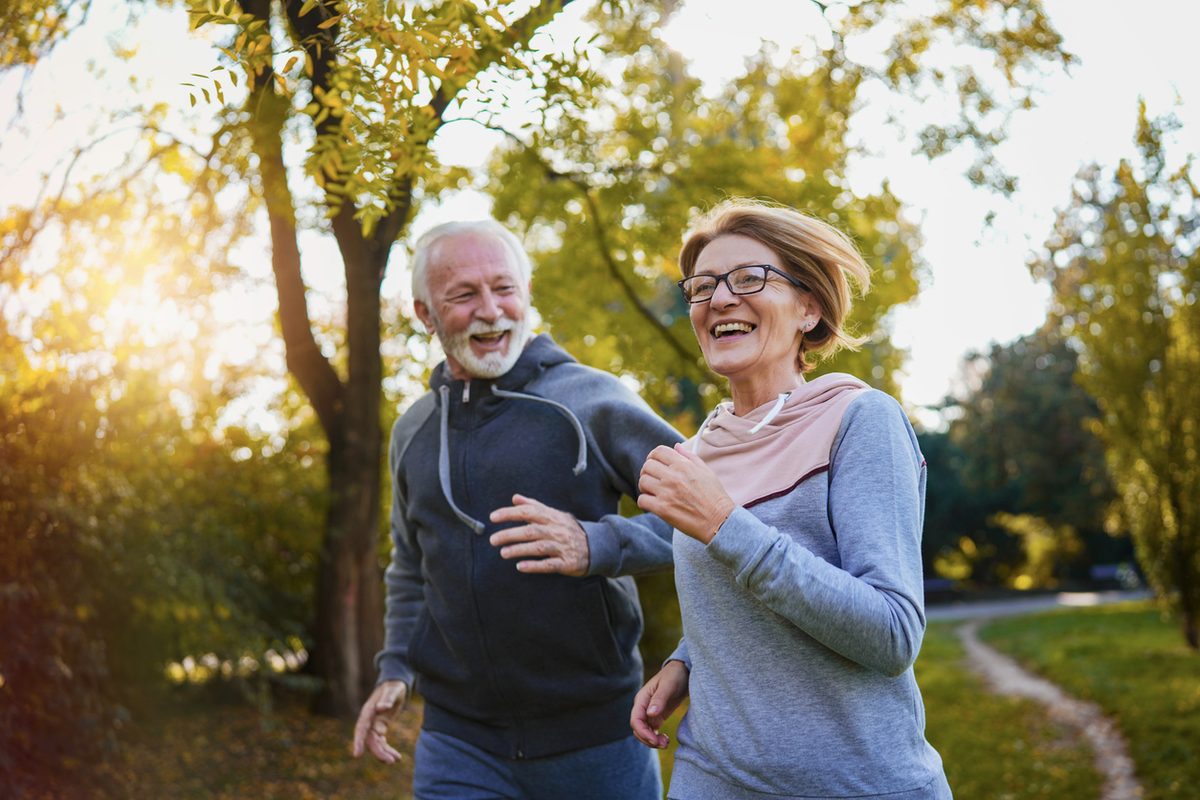 Older couple laughing while jogging together in a park