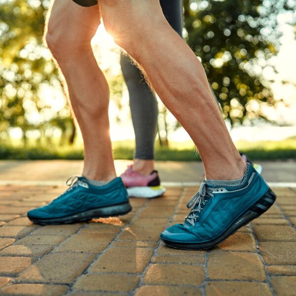 Close-up of feet and ankles in running shoes on a brick path