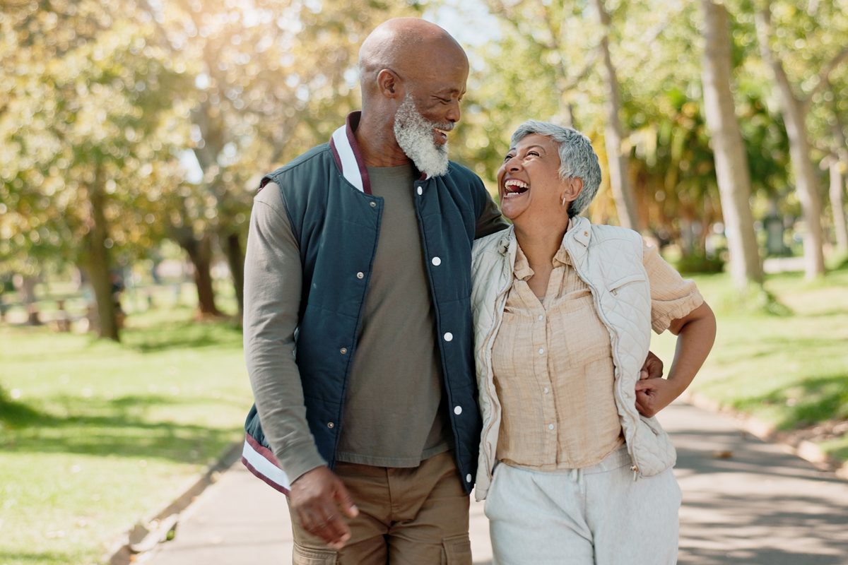 Senior couple laughing on a park walk