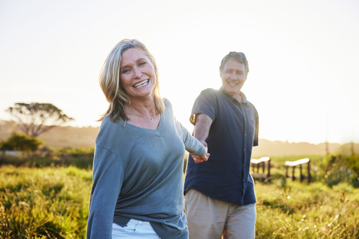 Smiling couple walking hand in hand through a sunny meadow