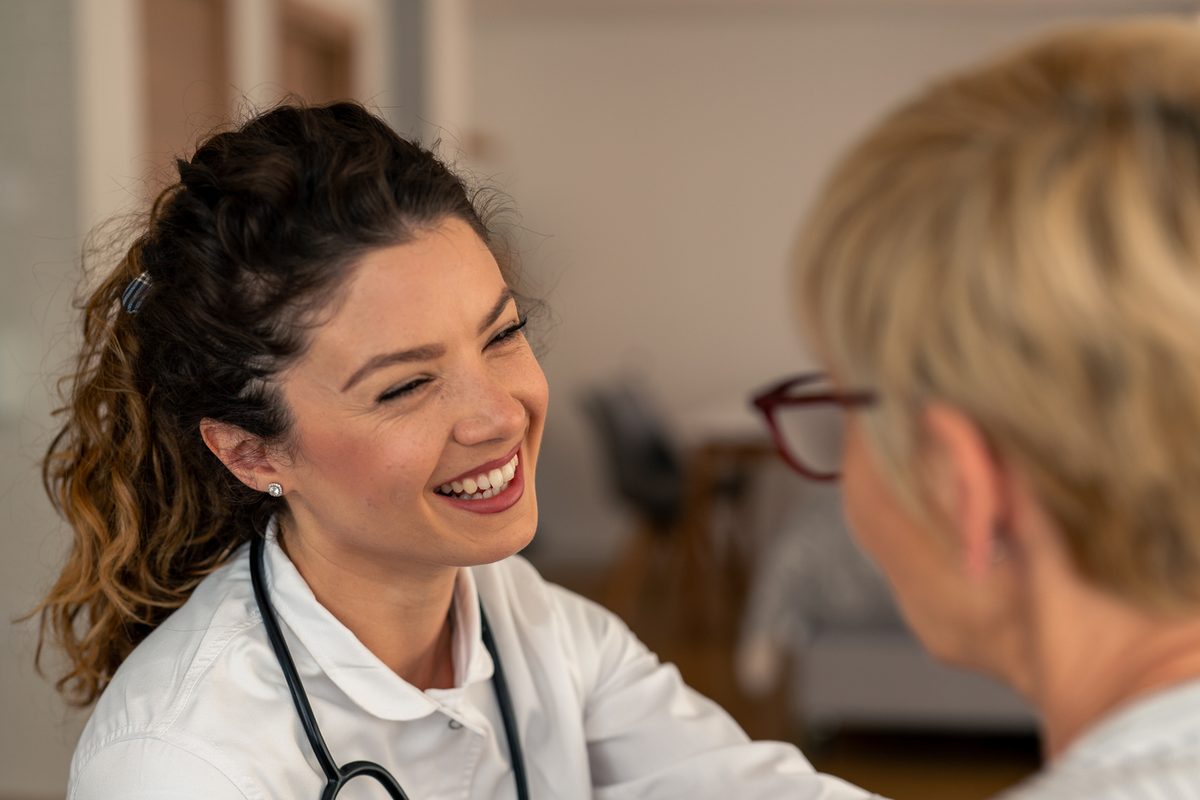 A smiling doctor talks with a woman patient