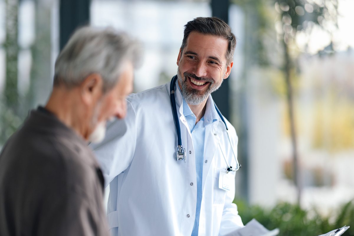 A smiling doctor talks with an older male patient during a visit