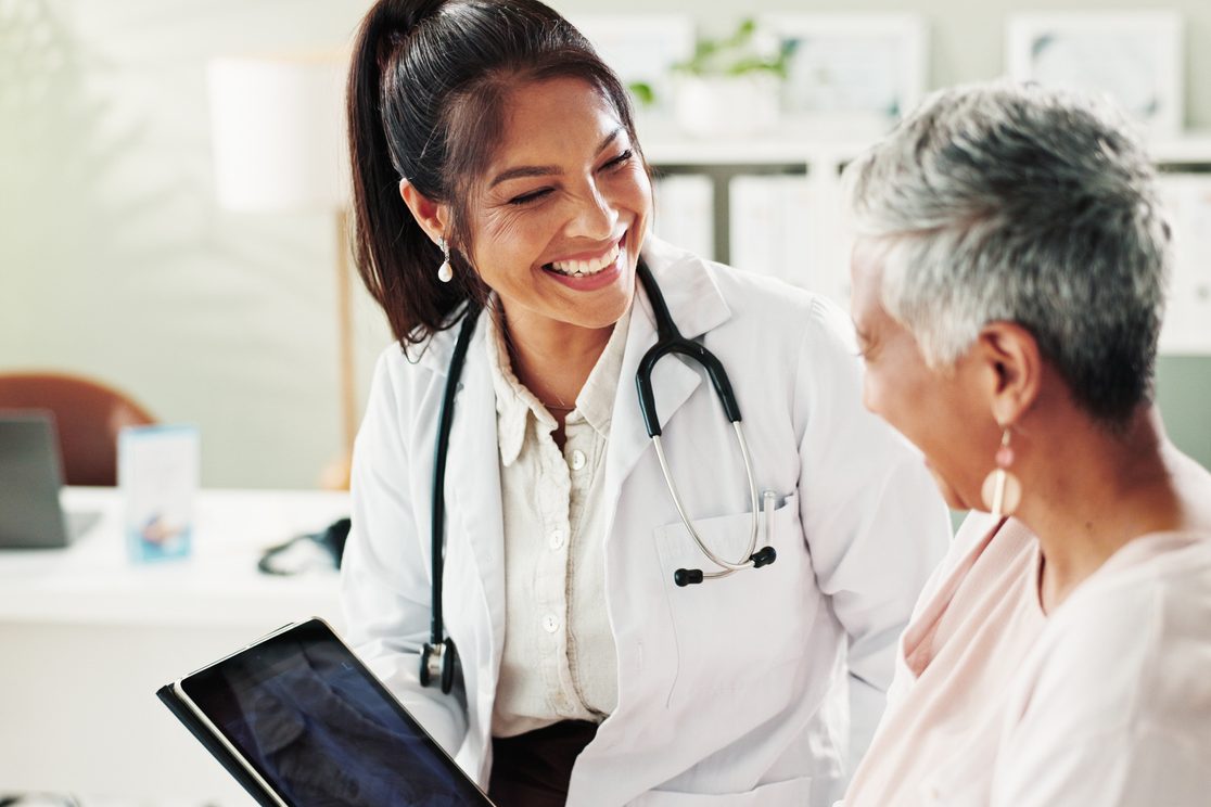 A smiling doctor reviews results with an older woman during a follow-up visit