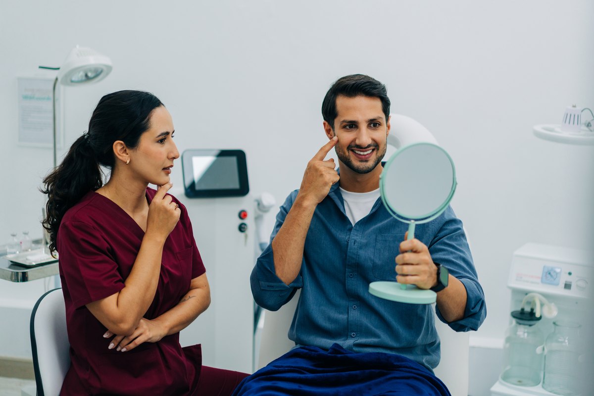 Smiling man checking his hair in a mirror with a clinician