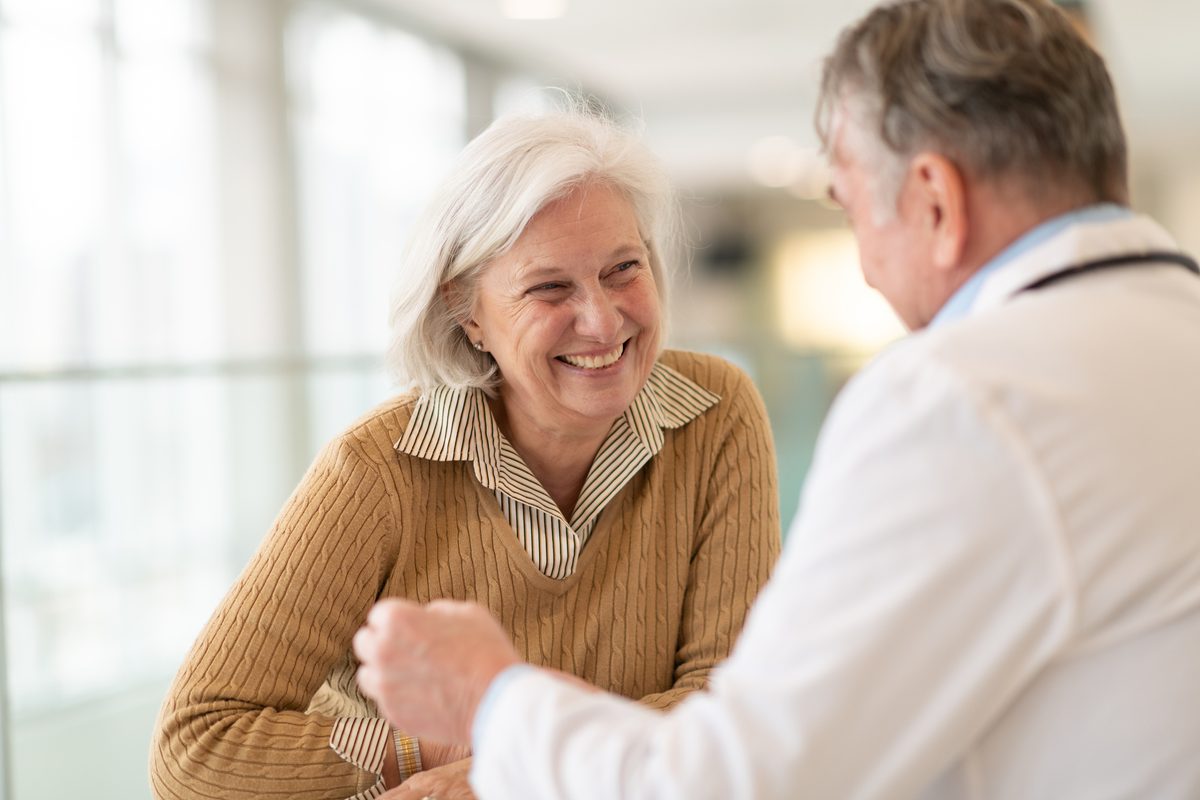 A smiling older woman talks with her doctor