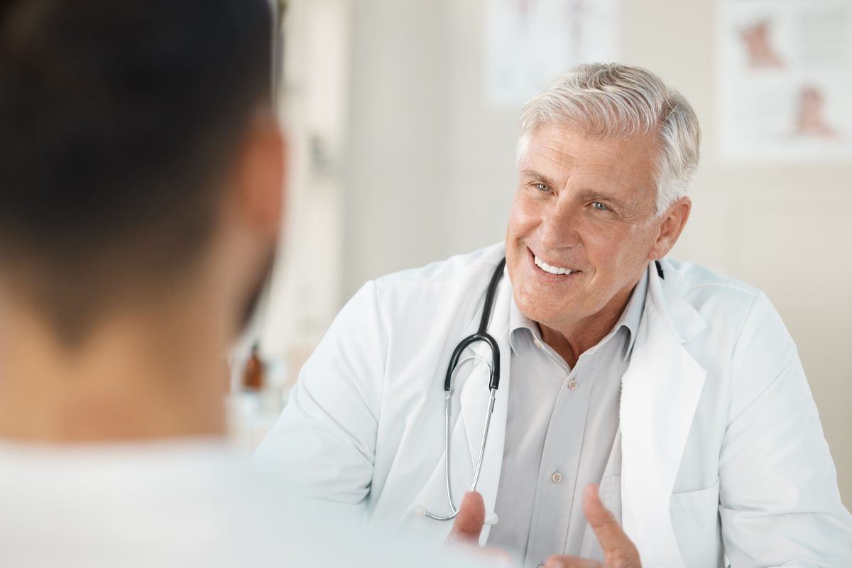 A smiling senior doctor talks with a patient