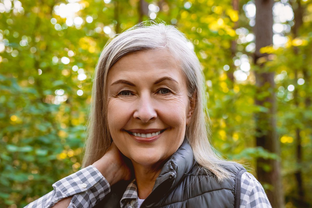 A smiling woman enjoys a walk in an autumn forest