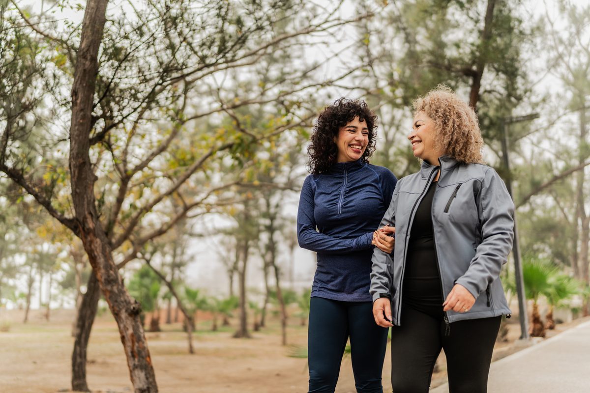 Two women walking arm in arm through a park
